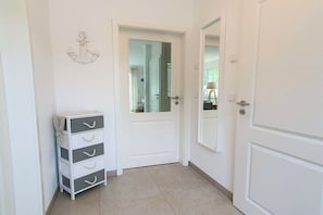 A hallway with a white door, a small white dresser with drawers, and a wall-mounted decorative anchor. - Holiday home in Prerow with swimming pool (Prerow)