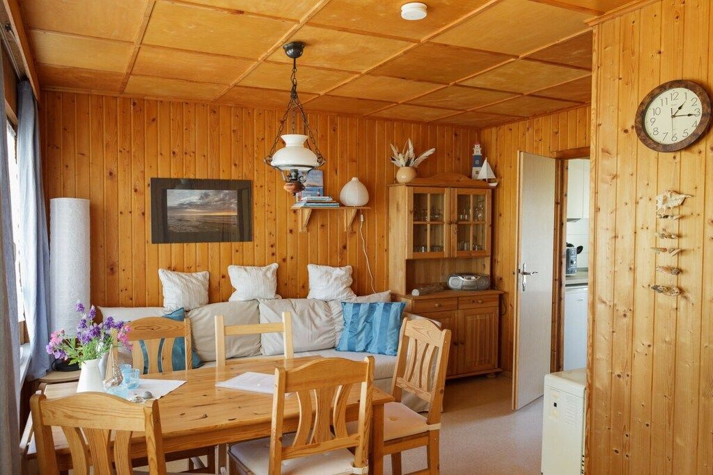 A wooden cabin interior with a dining area, a sofa, and a kitchen area.