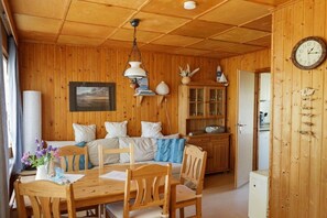 Ein Interieur einer Holzhütte mit Essbereich, einer Couch und einer Küchenzeile.