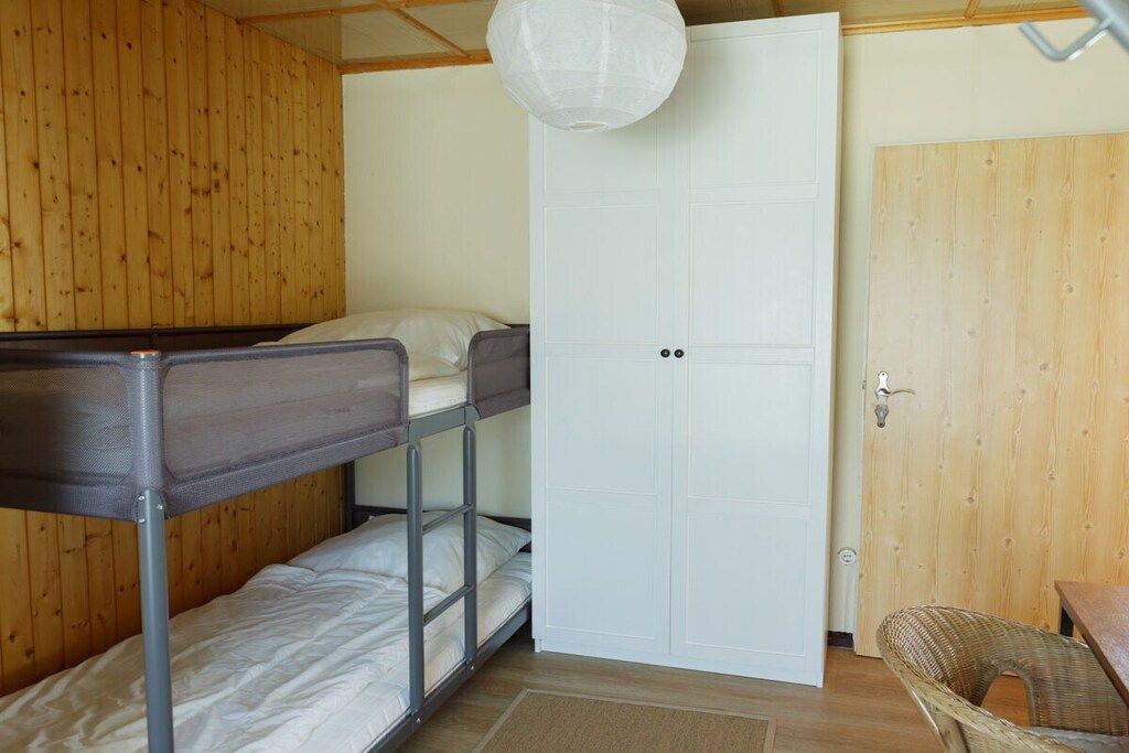 A room with bunk beds, a white door, and a wicker chair.