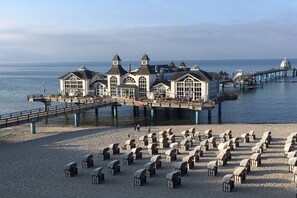 A coastal building with a pier extending into the water, surrounded by beach chairs. - Villa Louisa 43 - Octopussy (Ostseebad Sellin)