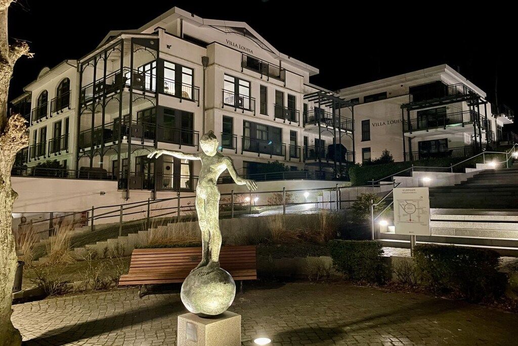 A building named 'Villa Louisa' with a statue of a figure balancing on a sphere.