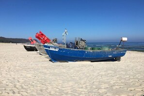 Un bote azul con el número de registro BAA-20 en una playa de arena.