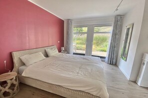 Un dormitorio con una cama grande, una ventana con cortinas y vistas a zonas verdes.