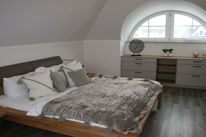 A bedroom with a bed, a dresser, a window, and a decorative item on the dresser. - Holiday apartment with 1 bedroom (Zingst)