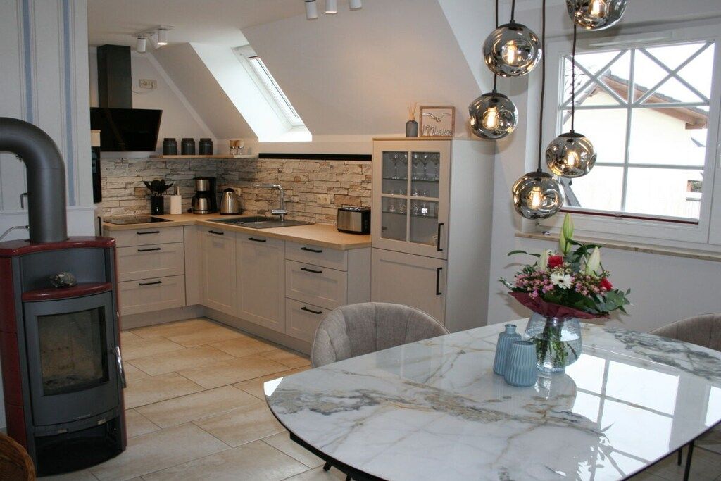 A modern kitchen with a stone backsplash, a built-in stove, and a dining area with a marble table.