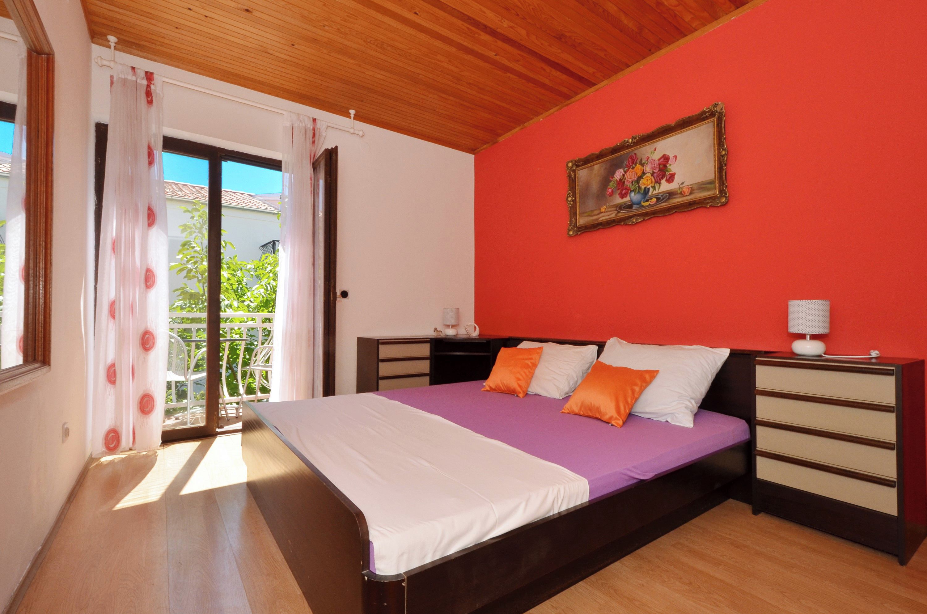 A bedroom with a bed, a nightstand, a dresser, and a painting on the wall.