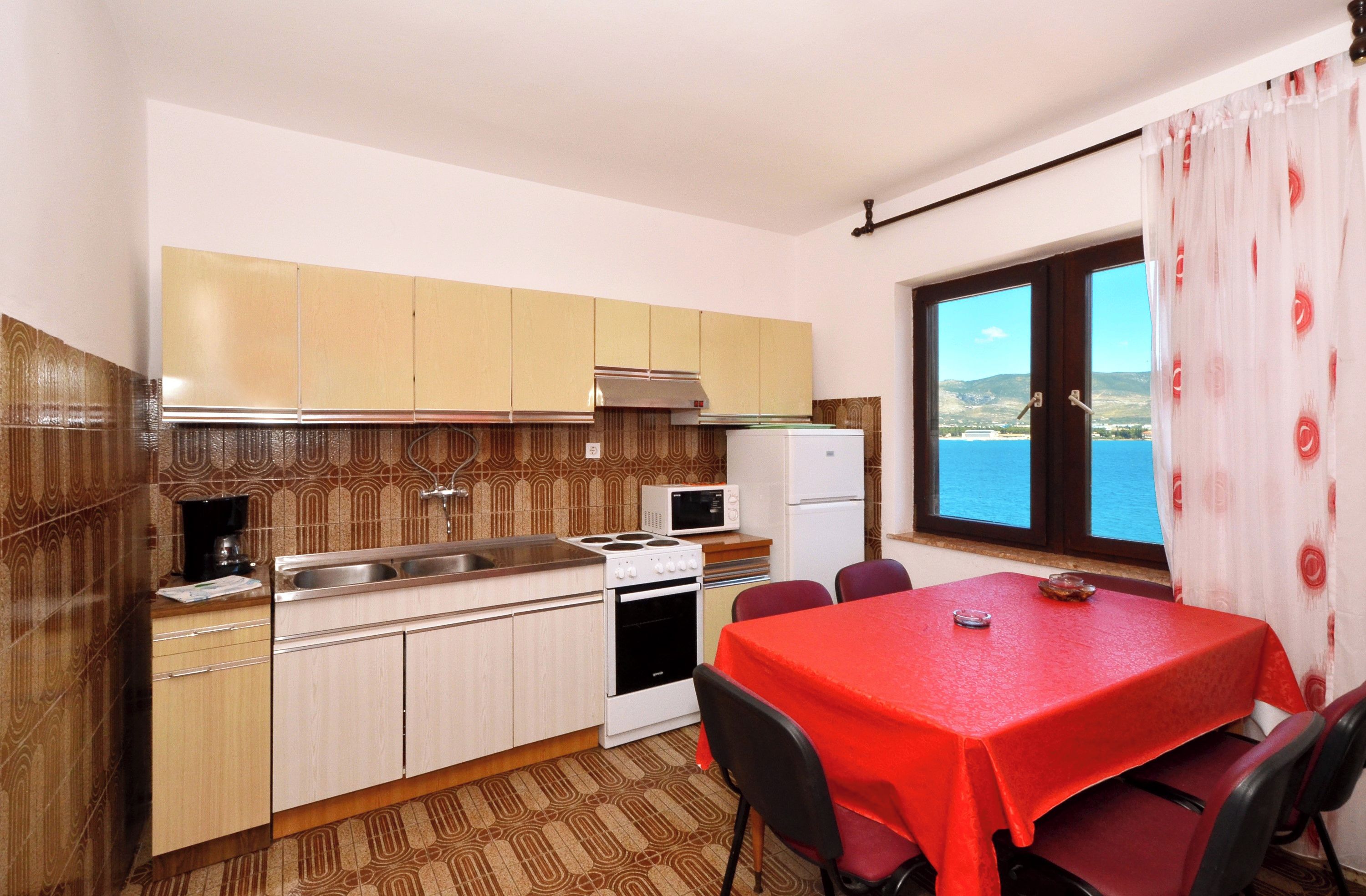 A compact kitchen with a dining area, featuring a stove, microwave, and refrigerator.