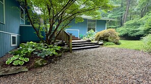 Une maison avec une allée en gravier menant à un escalier en bois.