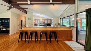 Une cuisine moderne avec un îlot central en bois, des tabourets de bar et une grande fenêtre.