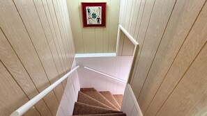 A wooden staircase with white handrails and a framed artwork on the wall.
