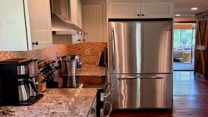 A modern kitchen with stainless steel appliances, a granite countertop, and a view to the living area.