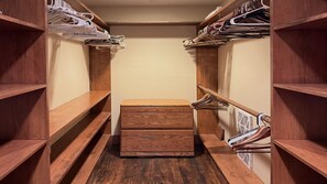 A walk-in closet with wooden shelves and a central drawer unit.