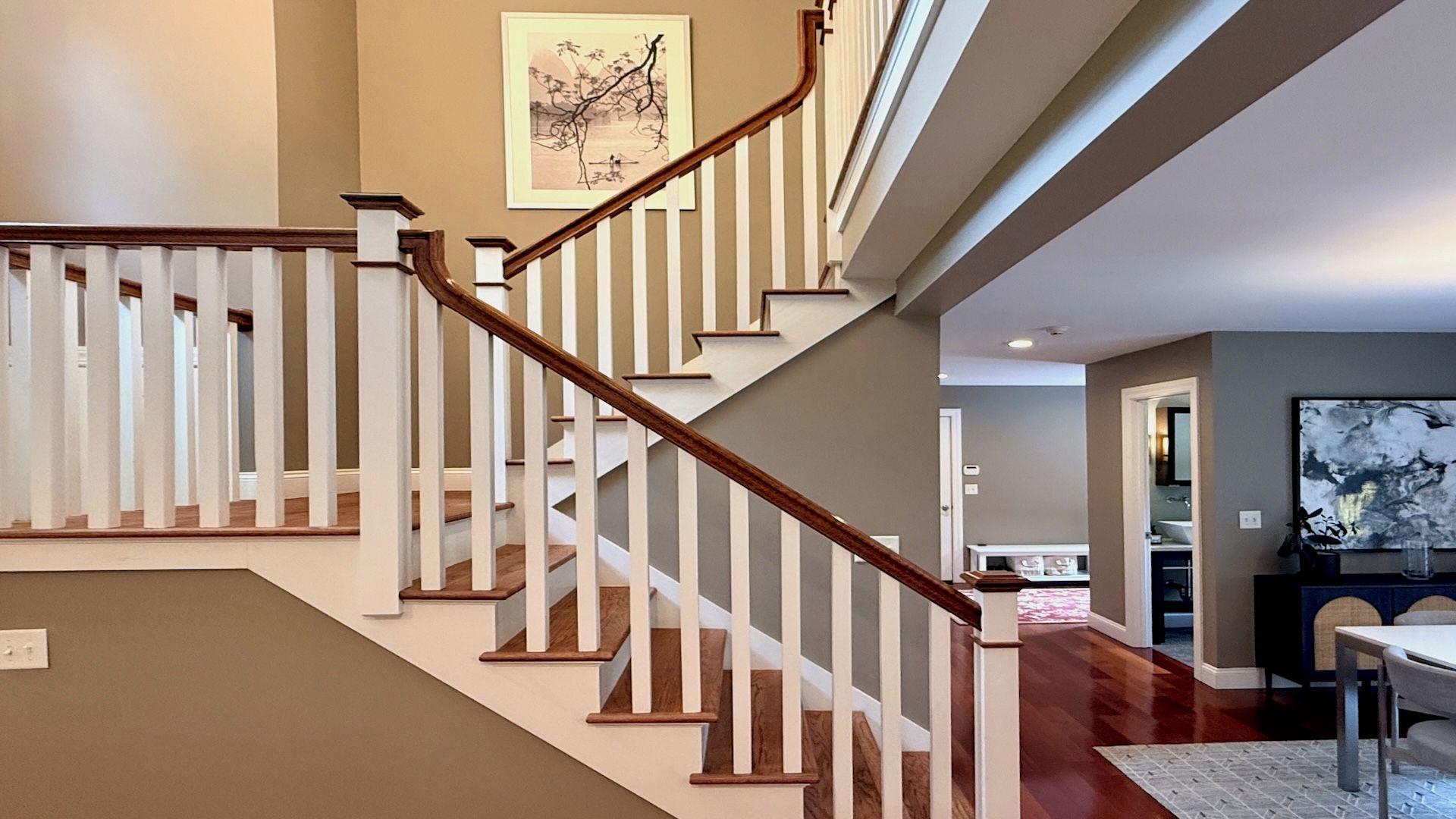A staircase with wooden handrails and white balusters leading to an upper floor.
