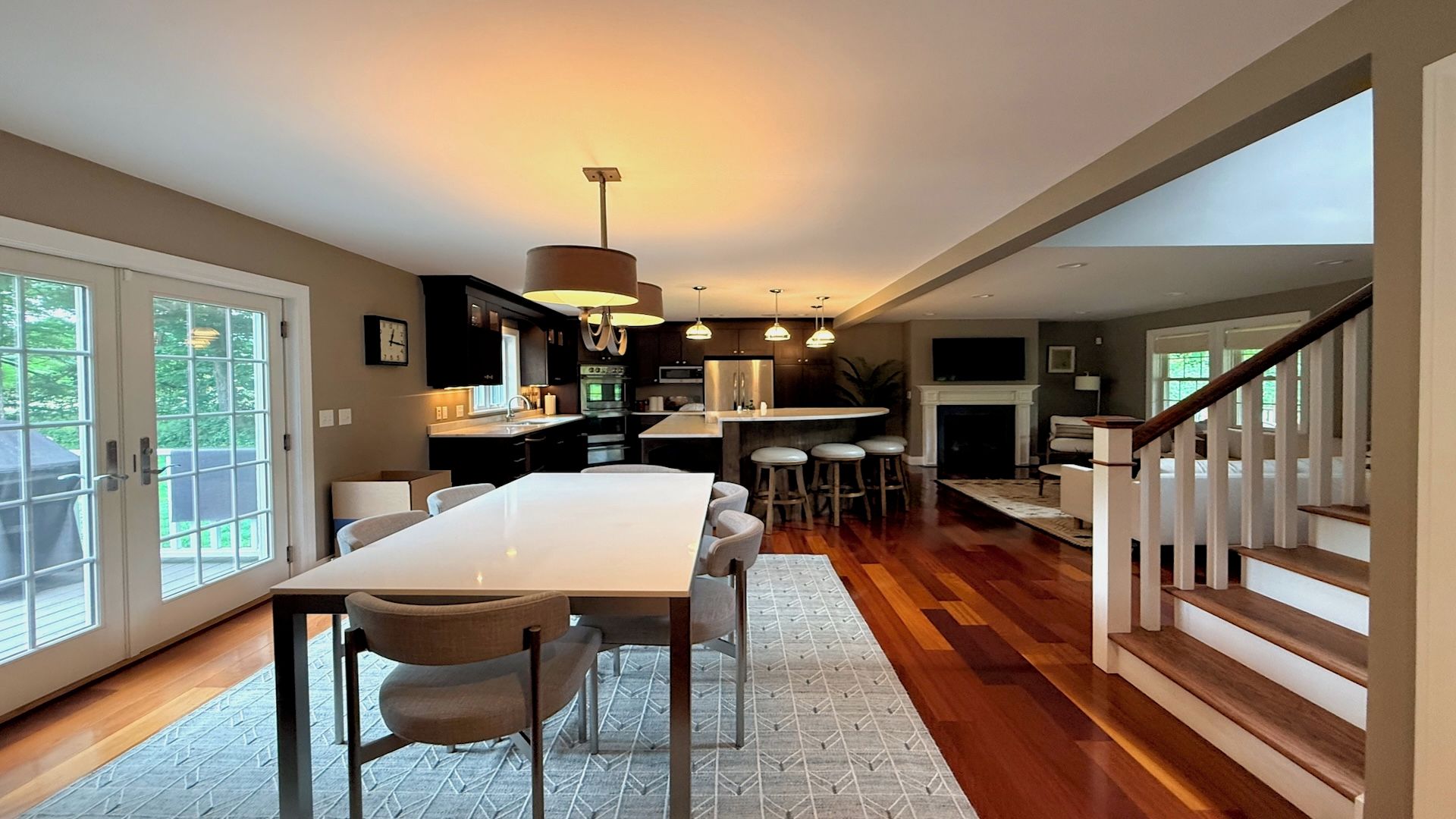 Een moderne keuken met een centraal eiland, een eetgedeelte met stoelen en een trap naar een hoger niveau.