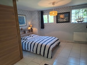 A bedroom with a bed, a window with curtains, a radiator, and a shelf with decorative items. - OCALME AGREABLE (SECLIN)