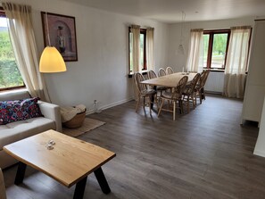 Ein Essbereich mit einem Holztisch und Stühlen, einem Sofa mit einem gemusterten Kissen und einer Lampe.