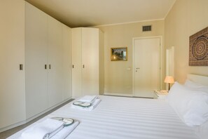 Ein Hotelzimmer mit einem Bett, einem Nachttisch, einer Lampe, einem Bild und einem Kleiderschrank.