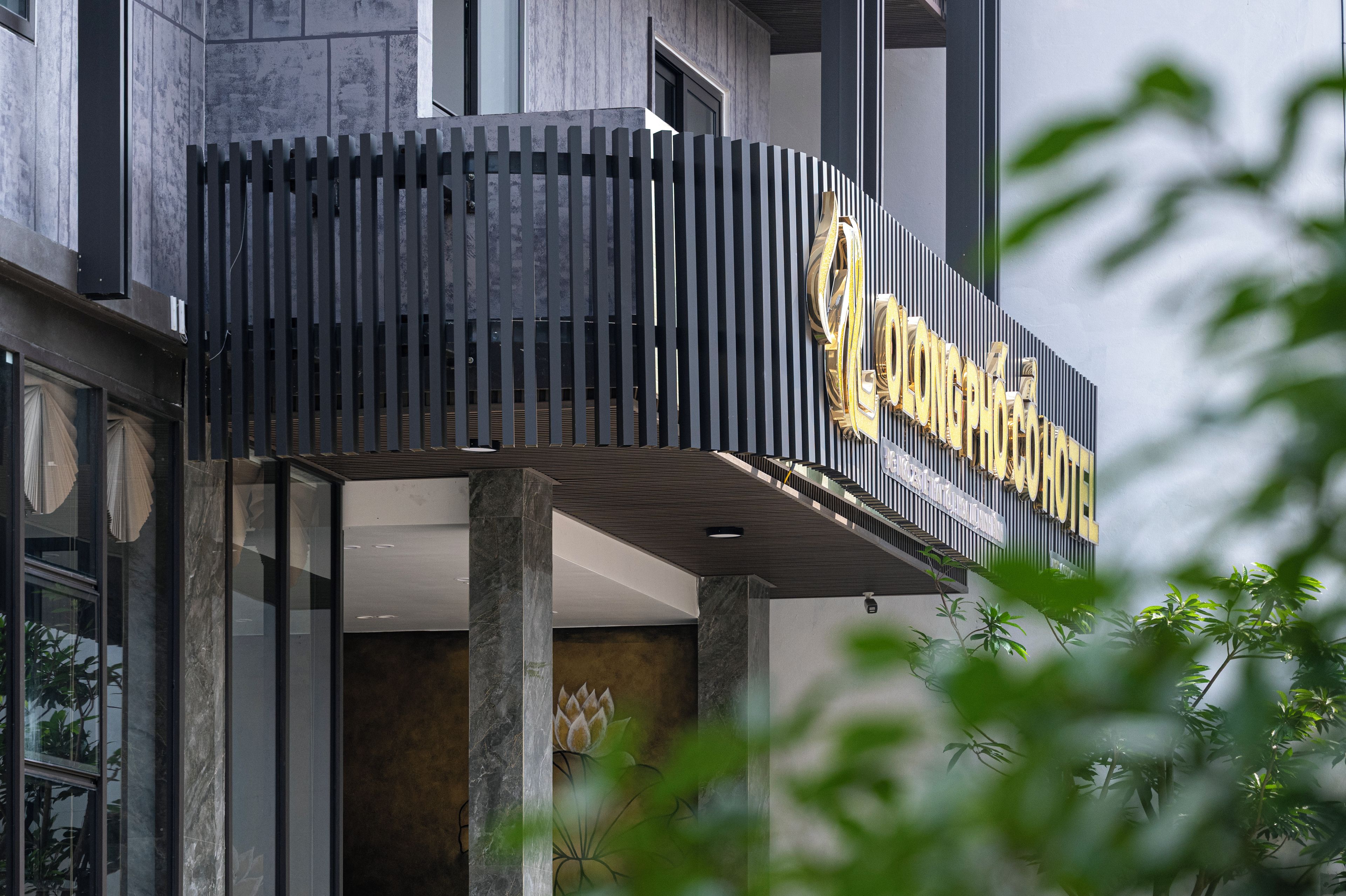 A hotel sign with a modern design, featuring vertical slats and a golden emblem.