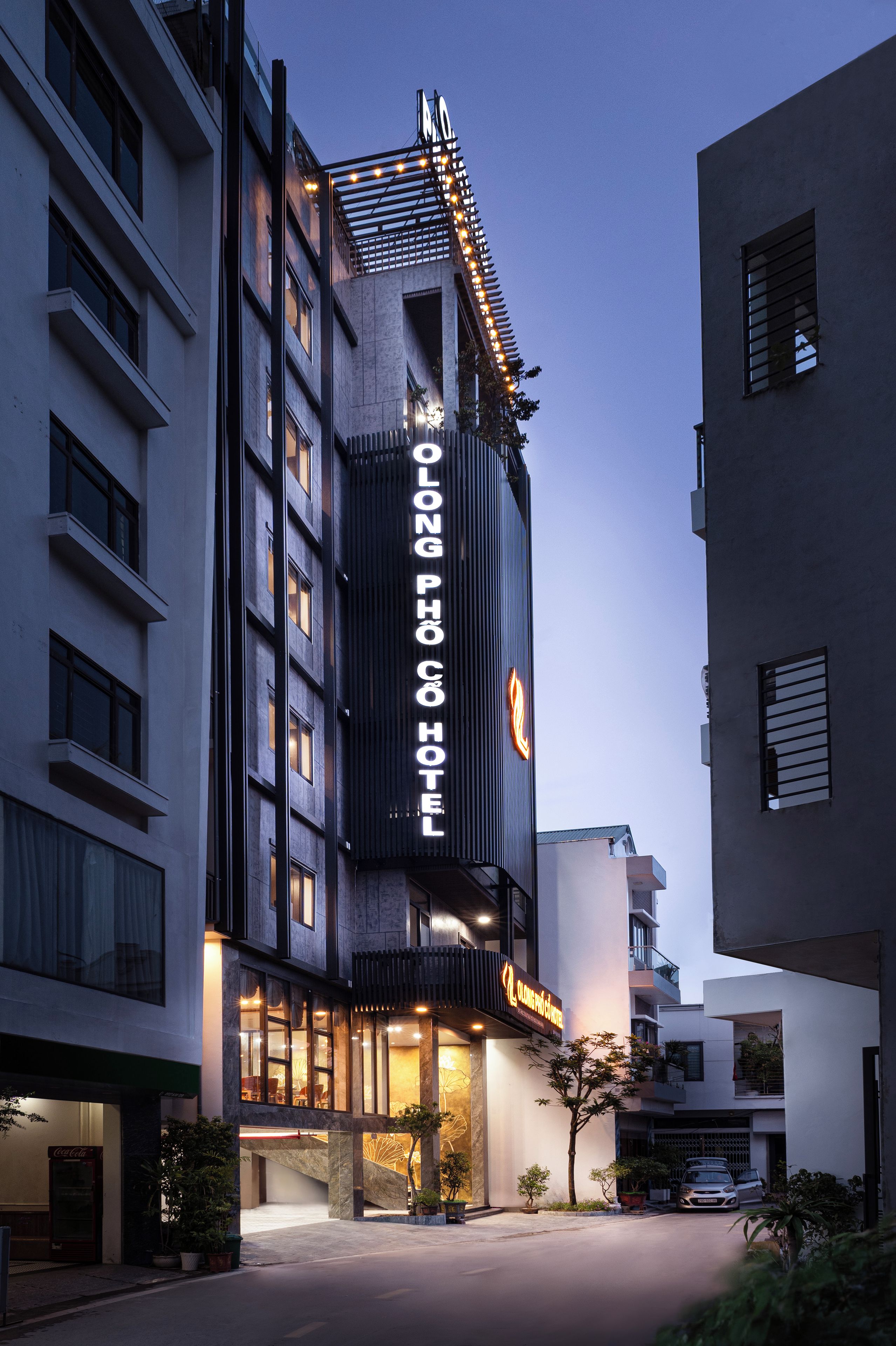Un hôtel doté d’une enseigne verticale bien visible, d’une façade moderne et d’une entrée bien éclairée.