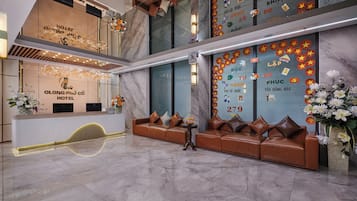 A hotel reception area with a reception desk, seating area, and decorative elements.