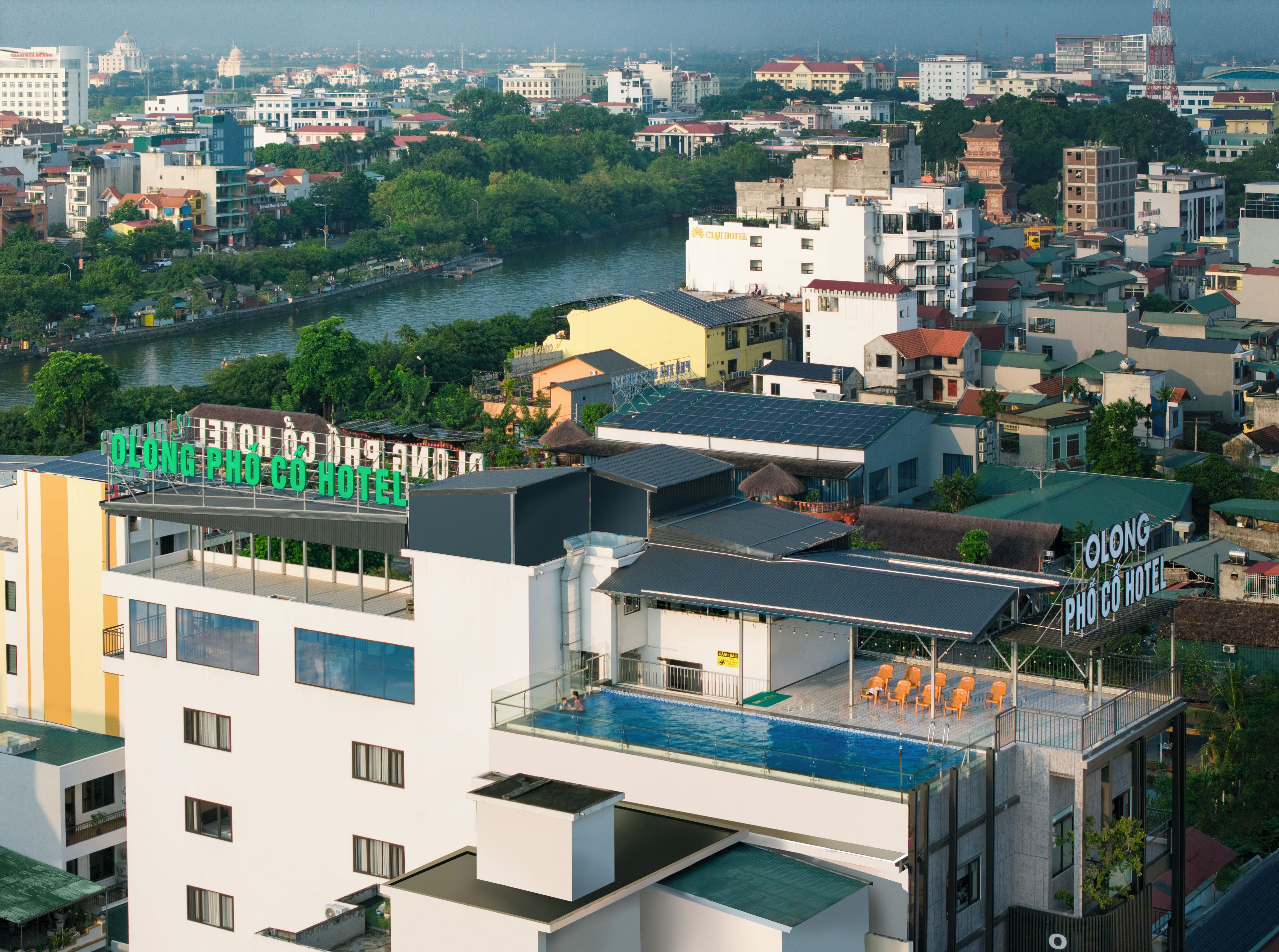 Um hotel com piscina no terraço e vista para a cidade.