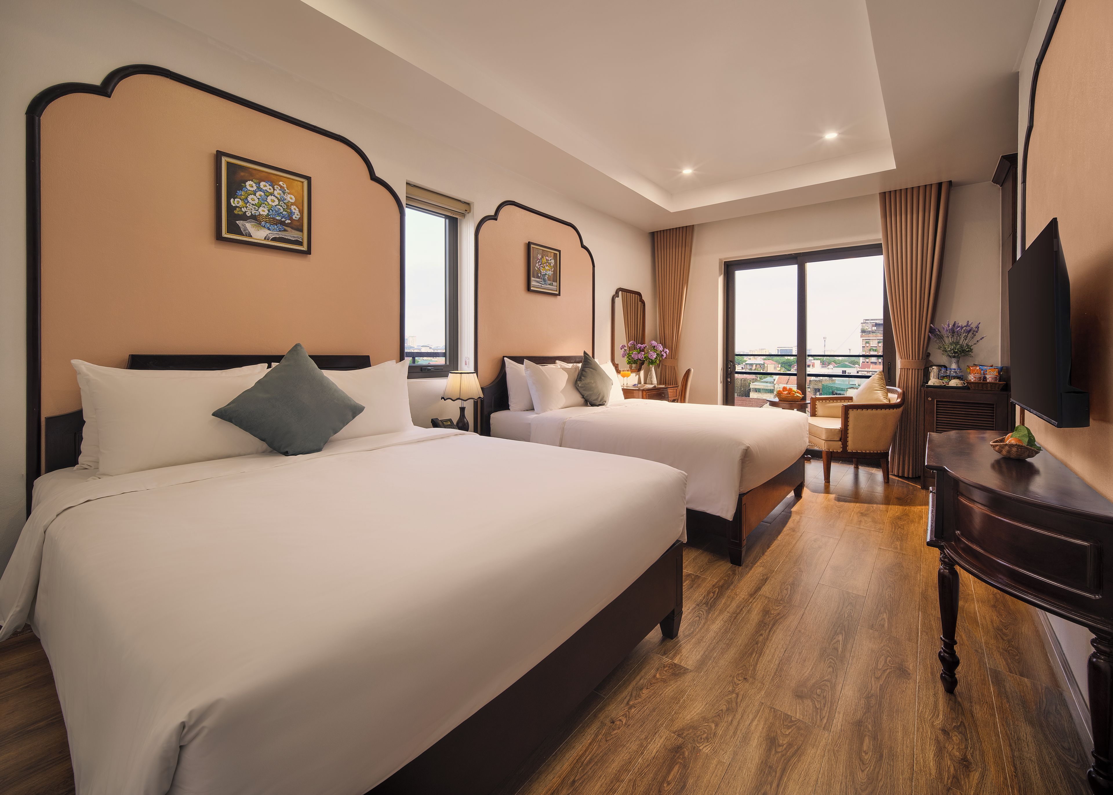 Une chambre d’hôtel avec deux lits, un bureau, une chaise, une télévision et une fenêtre donnant sur un beau paysage.