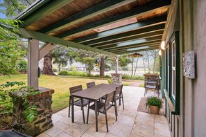 An outdoor patio with a covered seating area, stone pillars, and a view of the surrounding landscape. - Genie's Cottage - New Listing! (Cannon Beach)
