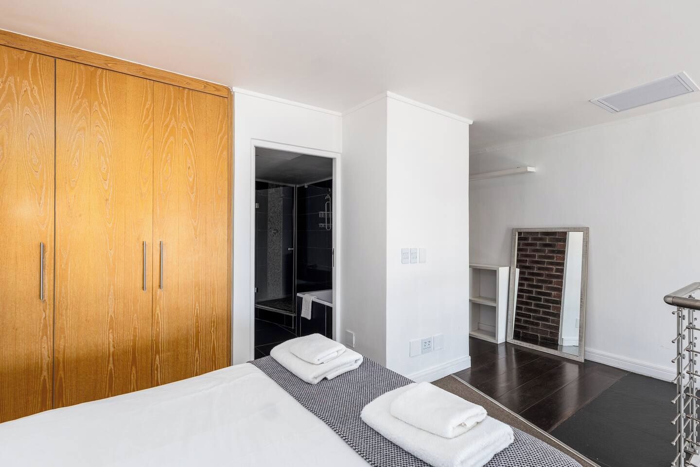 A hotel room with a bed, a wooden wardrobe, a shower area, and a brick fireplace.