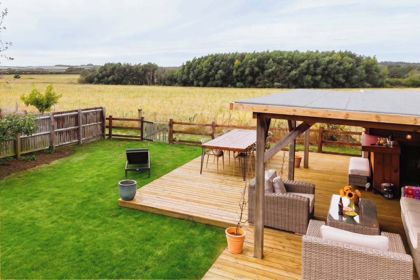 Une terrasse dotée de mobilier d’extérieur, d’un barbecue et offrant une vue sur un champ.