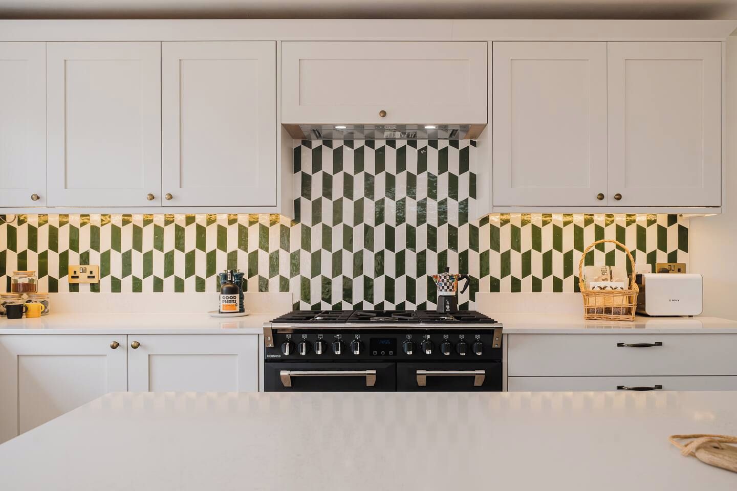Une cuisine avec des meubles blancs, une cuisinière noire et un pare-feu décoré.