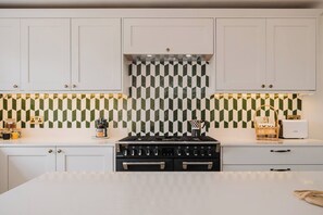 A kitchen with white cabinets, a black stove, and a patterned backsplash.