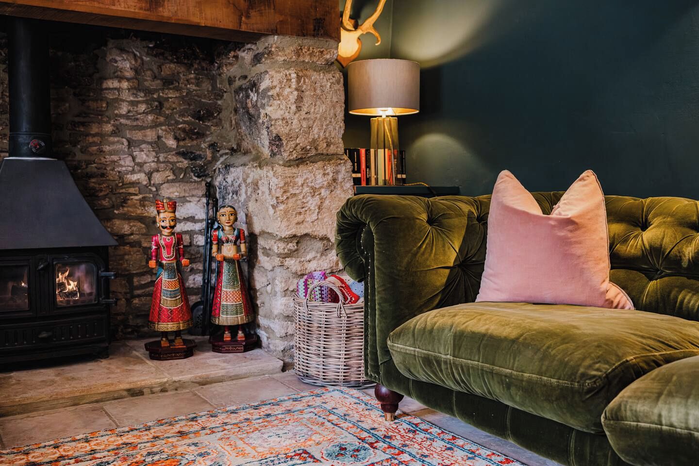 Un salon chaleureux avec une cheminée en pierre, un canapé vert moelleux et des figurines en bois traditionnelles.
