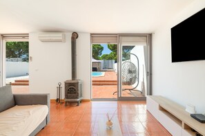 Un salon moderne avec un canapé, une cheminée, un téléviseur et une vue sur un espace piscine extérieur.