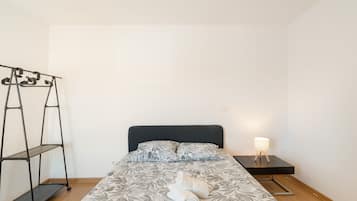 Un dormitorio con cama, mesita de noche, lámpara, armario y estantería.