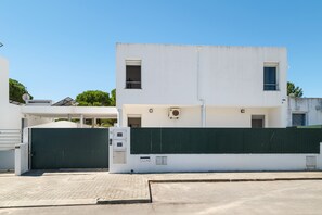 Un edificio moderno con fachada blanca, una verja verde y cielo despejado.
