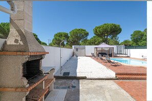 Un pati amb una barbacoa, una piscina i una zona d'estar coberta.
