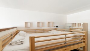 A minimalist bedroom with a bunk bed, a bedside table, a lamp, and a mirror. - GuestHost - Cozy Apartment in Milan (Milan)