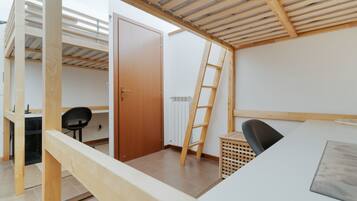 A room with a bunk bed, a desk, a chair, and a ladder.