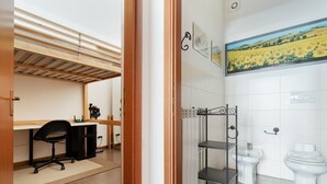 A room with a desk, chair, and a shelf unit in the corner. - GuestHost - Cozy Apartment in Milan (Milan)