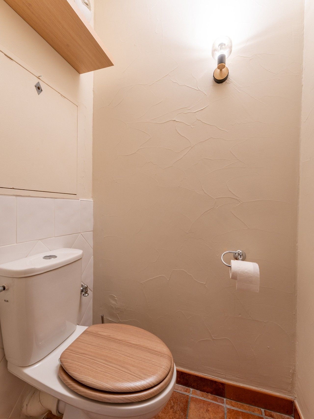 Un bagno con servizi igienici, lavandino e un portalampada a parete.