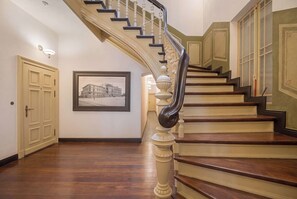 Eine prachtvolle Treppe mit geschwungener Handlauf, Holzstufen und einem gerahmten historischen Foto an der Wand.
