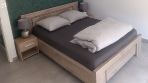 A bedroom with a bed, two bedside tables, a lamp, and a green textured wall. - Vrbo Property (Holtzheim)