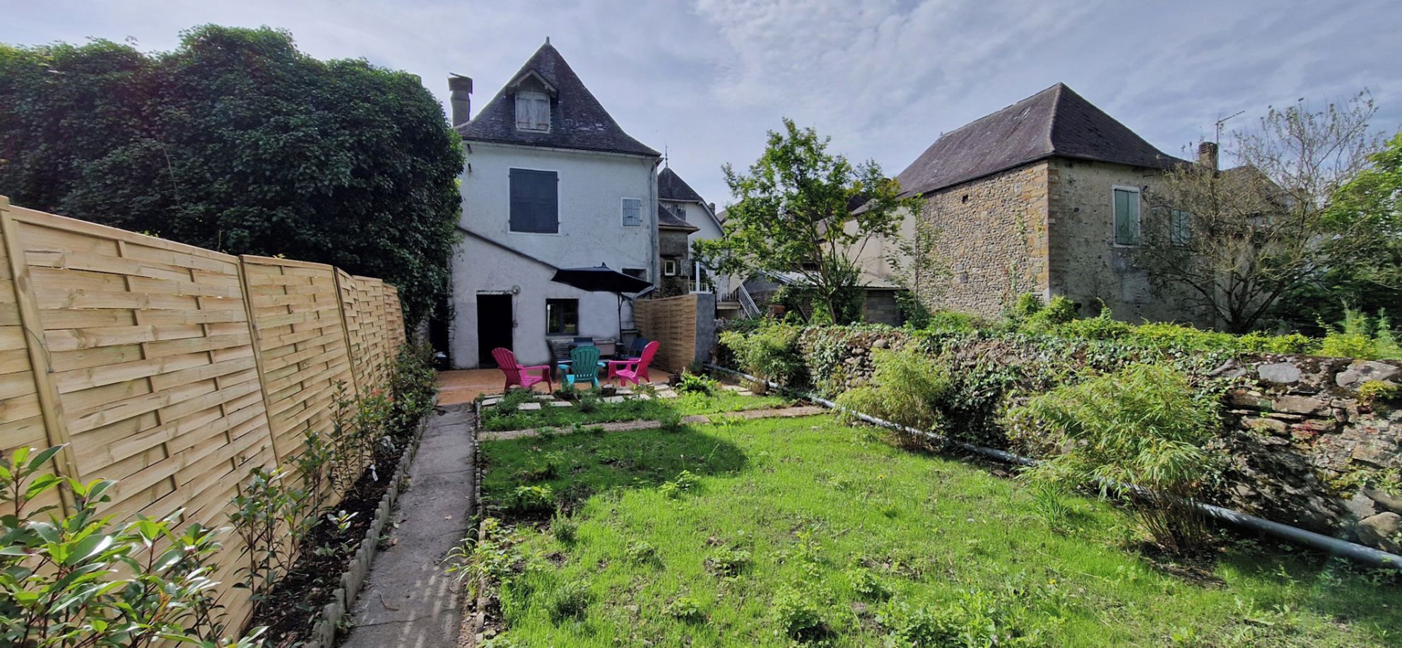 Il s’agit d’une propriété résidentielle dotée d’une allée pavée, d’une clôture en bois et d’une cour gazonnée avec un espace patio.