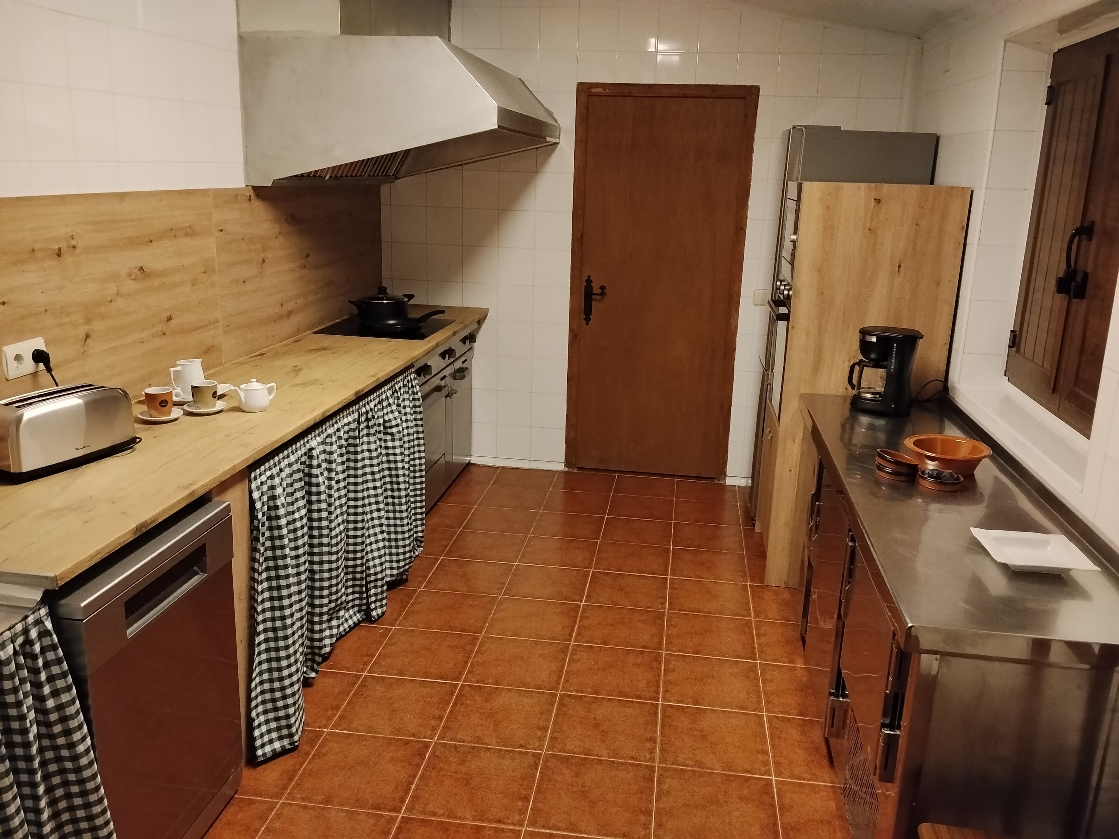 Cocina compacta con encimera de madera, estufa de acero inoxidable y salpicadero de azulejos.