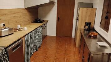 Cocina compacta con encimera de madera, estufa de acero inoxidable y salpicadero de azulejos.