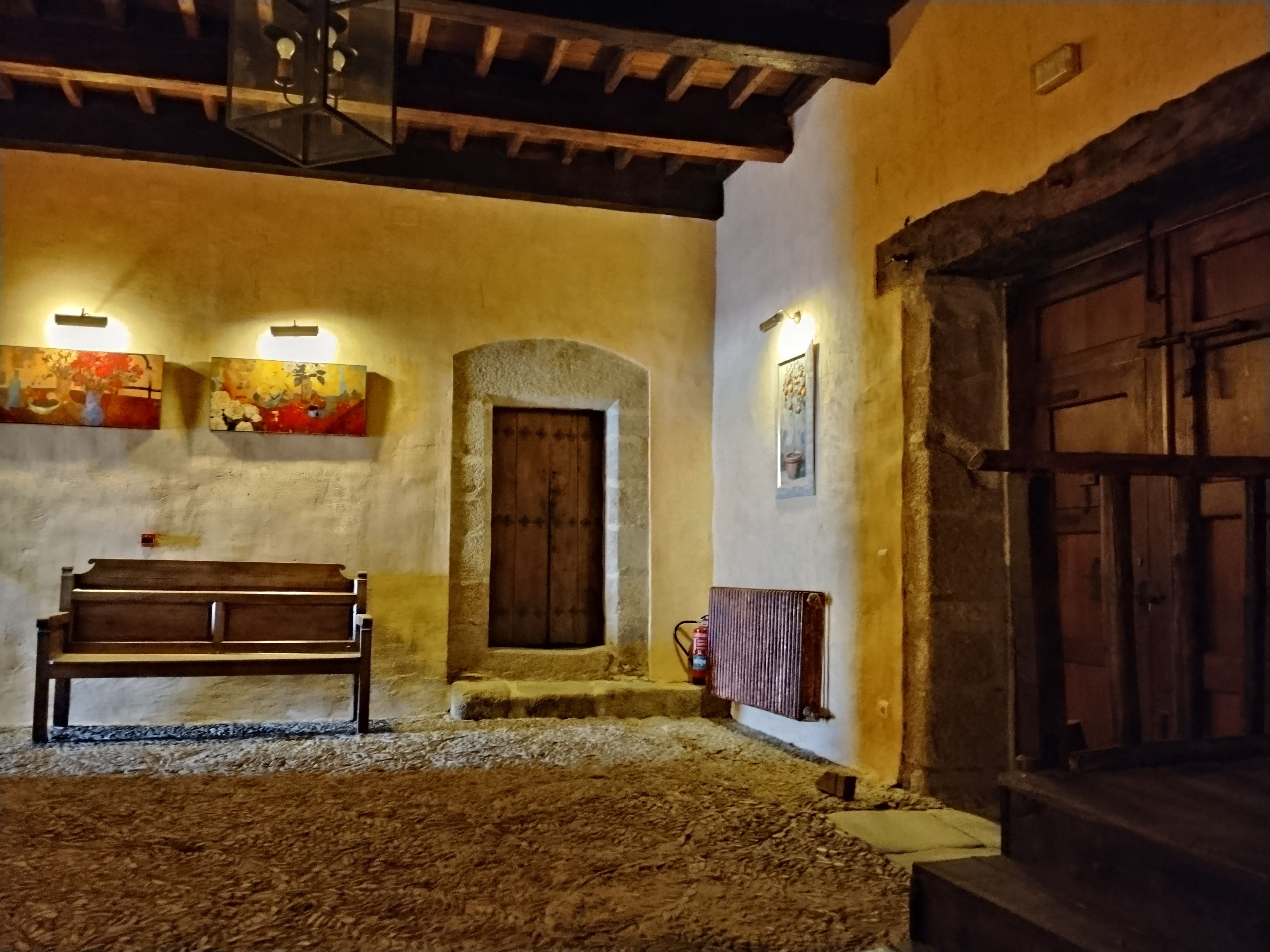 Un interior rústico con un banco de madera, un arco de piedra y una puerta de madera.