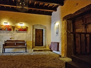 A rustic interior with a wooden bench, a stone archway, and a wooden door.
