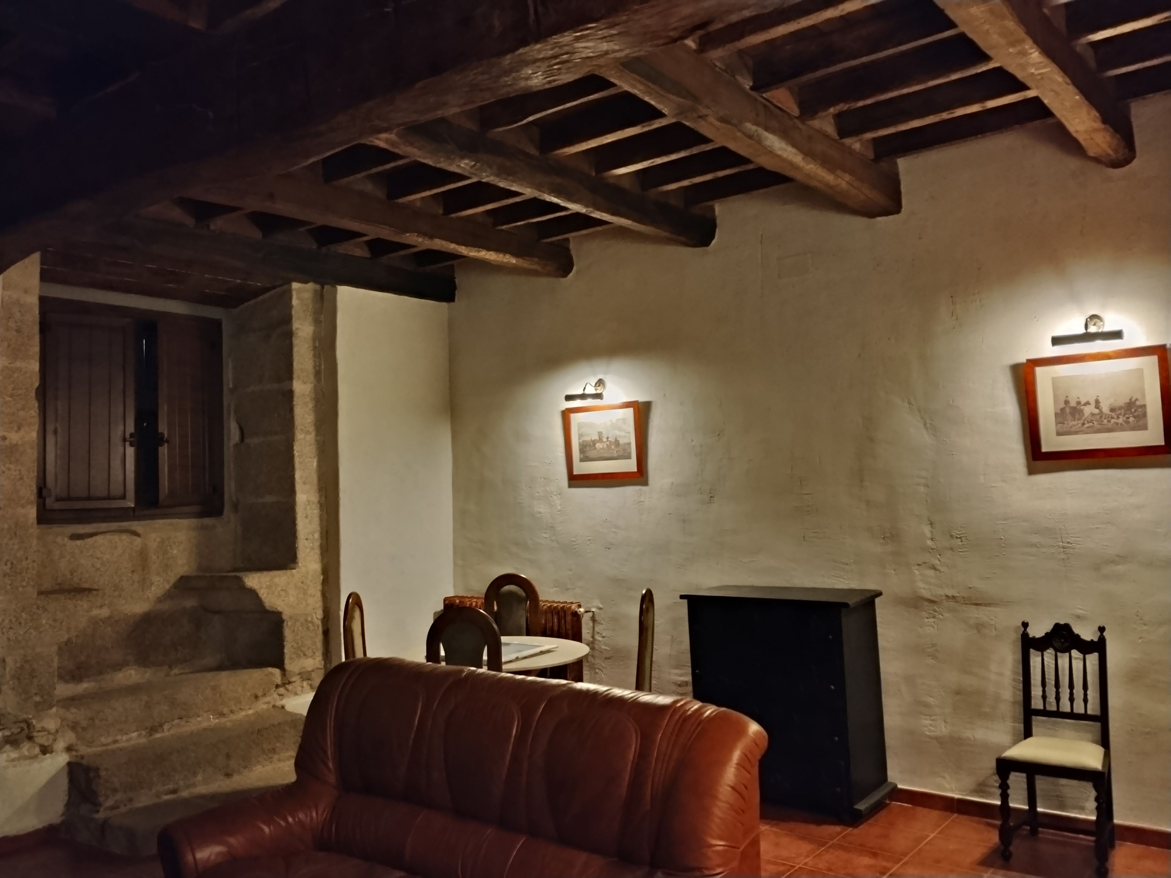 Una habitación con chimenea, un sofá de cuero, una mesa de comedor con sillas y una escalera.