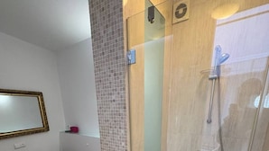 Ein modernes Badezimmer mit einer gläsernen Duschkabine, einem Holzwaschtisch und einem gefliesten Boden.